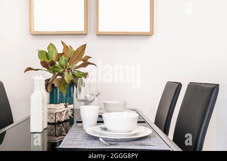 Tavolo da pranzo in vetro nero con servizio per due in un appartamento in affitto per le vacanze Foto Stock