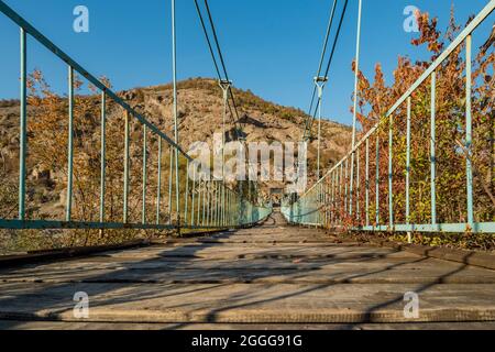 Ponte pedonale sospeso in legno e metallo verniciato blu con ruggine su un fiume nel sud della Bulgaria Foto Stock