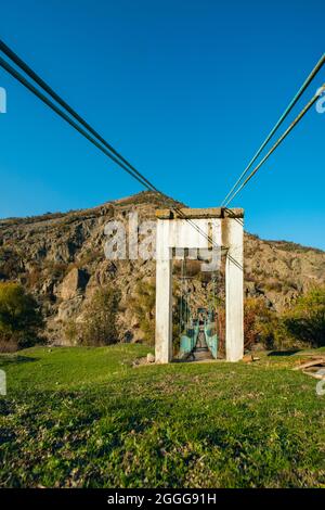 Paesaggio montuoso con un vecchio ponte pedonale in legno e metallo dipinto su un affluente del fiume Arda in Bulgaria. Foto Stock