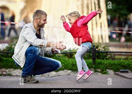 La ragazza felice del toddler gioca con il padre nel parco vicino alla fontana. Foto Stock