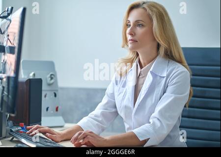 Bel medico biondo si è concentrato sul controllo della sua e-mail Foto Stock