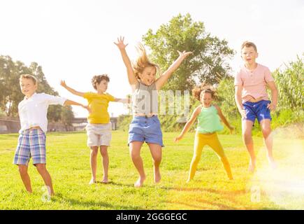 I bambini saltano e alzano le mani Foto Stock