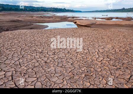 Terra spaccata vicino all'acqua di essiccazione al crepuscolo a Sam Pan Bok nel fiume Mekong. Provincia di Ubonratchathani, Thailandia Foto Stock