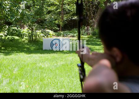 Ragazzo giovane che pratica il tiro con l'arco nel cortile di casa - USA Foto Stock