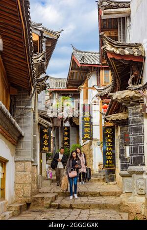 Yunnan, Cina - 22 marzo 2016: Turisti che camminano lungo la strada di negozi storici nella città antica di Lijiang. Foto Stock