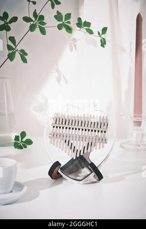 Kalimba o mbira è uno strumento musicale africano. Vetro Kalimba 17 tasti su stand e su tavolo bianco decorazione con foglie verdi. Stile di concetto. Musi Foto Stock