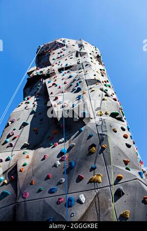 alto muro di arrampicata con funi e varie sporgenze Foto Stock