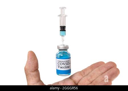 Una mano con flaconcino di vetro levitante etichettato coronavirus COVID-19 Vaccine e una siringa di vetro e un ago, isolato su sfondo bianco, fo levitation Foto Stock