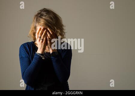 FOTO POSATA DAL MODELLO file foto datata 09/03/15 di una donna con la testa nelle mani. Lo stress sul lavoro, i disturbi del sonno e la fatica, considerati come fattori di rischio non tradizionali per l'attacco di cuore e l'ictus, stanno aumentando in modo più ripido nelle donne che negli uomini, un nuovo studio suggerisce. I ricercatori hanno confrontato i dati di 22,000 uomini e donne nel sondaggio svizzero sulla salute del 2007, 2012 e 2017 e hanno scoperto quello che hanno descritto come un allarmante aumento del numero di donne che segnalano i fattori di rischio non tradizionali per le malattie cardiovascolari. Data di emissione: Mercoledì 1 settembre 2021. Foto Stock