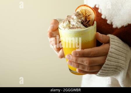 Donna in maglione tiene un bicchiere di latte di zucca Foto Stock