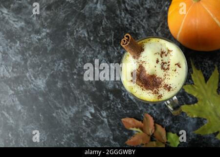 Bicchiere di latte di zucca, zucca e foglie su tavola nera di smokey Foto Stock