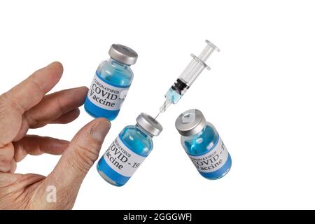 Mano con flaconcini di vetro levitante etichettati coronavirus COVID-19 Vaccine e una siringa di vetro e un ago, isolati su sfondo bianco, levitazione. Foto Stock