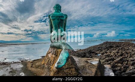 La famosa statua della sirena chiamata 'la Sirena' creata da uno scultore locale Albino Valverde fotografato da dietro. L'aletta è rotta. Durante la bassa marea. Foto Stock