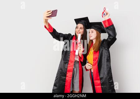 Due belle studentesse, celebrando la loro laurea e facendo selfie. Foto di alta qualità Foto Stock