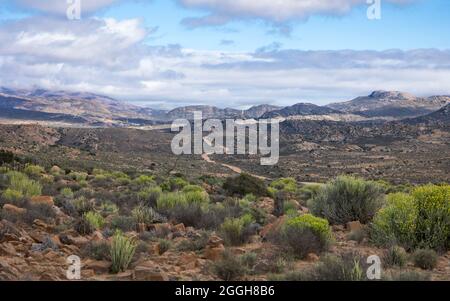 Paesaggio di una strada sterrata che conduce attraverso le montagne di Kamiesburg con un cielo nuvoloso Foto Stock