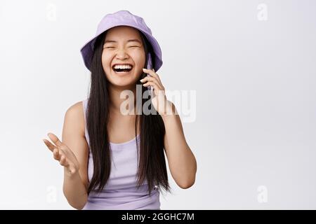 Ridendo ragazza asiatica parla sul telefono cellulare, godendo di conversazione. Concetto di smartphone e tecnologia cellulare Foto Stock