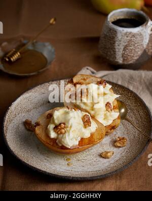 Dolce dessert rustico. Pere arrosto con panna e noci su sfondo di legno. Miele e caffè Foto Stock