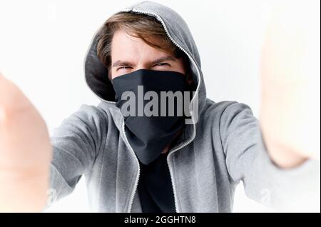 uomo che nasconde il suo volto sotto una maschera con un cappuccio anonimato crimine furto primo piano Foto Stock