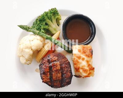 Delizioso filetto di bistecca mignon servito con salsa, baby corn, pasticceria, broccoli, cavolfiore e asparagi in un piatto al ristorante. Foto Stock