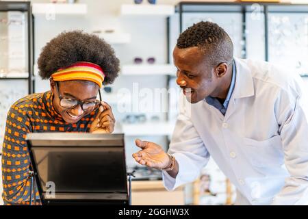 Uomo professionista ottico aiutare e vendere giovane donna scelta occhiali occhiali occhiali Foto Stock