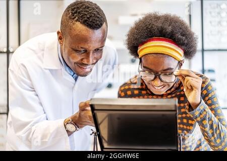 Uomo professionista ottico aiutare e vendere giovane donna scelta occhiali occhiali in negozio Foto Stock