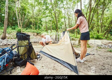 Felice coppia sportiva che prepara il campo vicino al ruscello Foto Stock