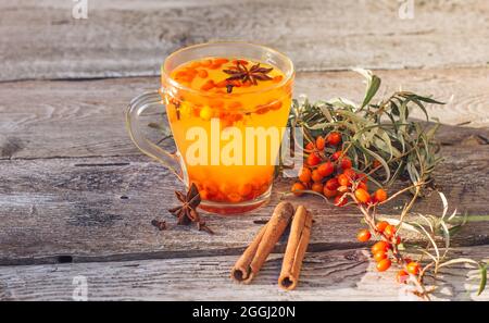 Vitamina calda Mare buckthorn tè in una tazza, si trova su un vecchio sfondo legnoso. Relax e medicina di erbe, anti-freddo drink, stagione influenzale Foto Stock