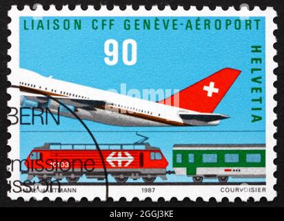 SVIZZERA - CIRCA 1987: Un francobollo stampato in Svizzera mostra aereo e treno, aeroporto Cointrin-Ginevra, apertura del collegamento ferroviario, circa 1987 Foto Stock