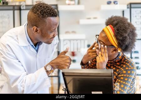 Uomo professionista ottico aiutare e vendere donna scelta occhiali occhiali occhiali in negozio ottico Foto Stock