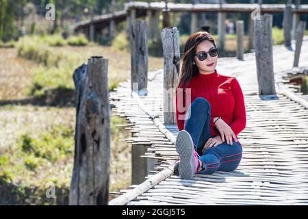 Donna tailandese seduta sul tradizionale lungomare di bambù nel nord della Thailandia Foto Stock