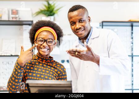 Professionista oftalmologo medico uomo aiutare giovane cliente donna a scegliere un occhiali è successo Foto Stock