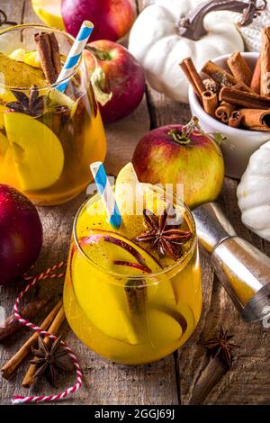Boozy Pumpkin Party Punch, sangria di ringraziamento con succo di zucca, mela, pera e spezie, fondo in legno accogliente con maglione caldo e ingredienti c Foto Stock