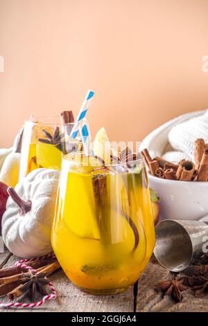 Boozy Pumpkin Party Punch, sangria di ringraziamento con succo di zucca, mela, pera e spezie, fondo in legno accogliente con maglione caldo e ingredienti c Foto Stock