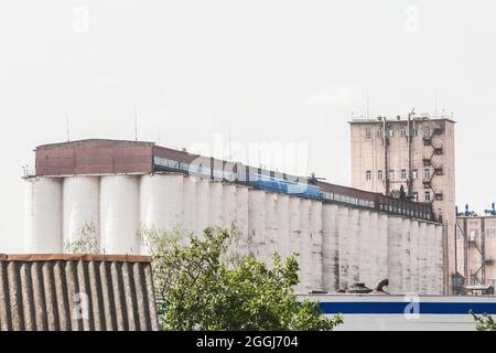 Impresa industriale in città con grandi torri di stoccaggio per lo stoccaggio di cereali, prodotti alimentari o chimici. Foto Stock