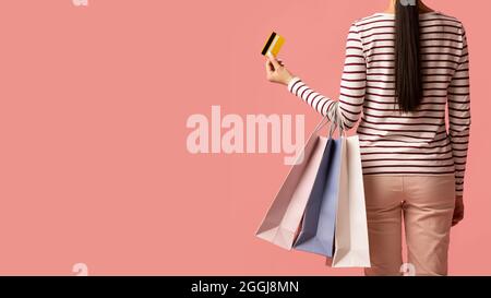 Vendite e sconti. Donna che tiene i sacchetti di shopping e la carta di credito, vista posteriore Foto Stock