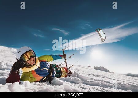 Il kite surfer adulto si trova sulla neve con il kite in mano e sorridere. Concetto di snowkiting con sci o snowboard Foto Stock