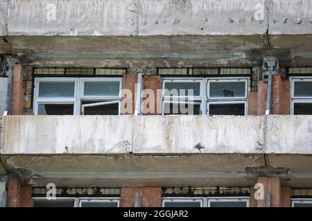 Abbandonato edificio sgretolante con balconi semicircolari - pericolo di collasso. Primo piano del frammento. Foto Stock
