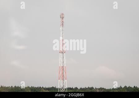 Torre di comunicazione di dispositivi mobili e cellulari con antenne sullo sfondo di un cielo grigio. Foto Stock