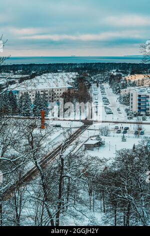 Una vista dalla costa arrociata (costa abrasiva) su Haabneeme insediamento con un parcheggio tra i parchi durante una fredda serata invernale. Foto Stock