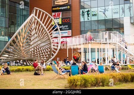 POZNAN, POLONIA - 26 ago 2018: Un gruppo di persone che siedono vicino al centro commerciale Galeria Malta a Poznan, Polonia Foto Stock