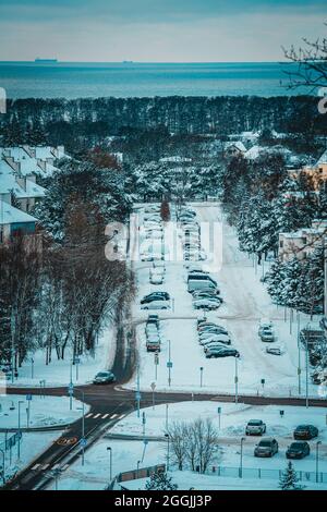 Una vista dalla costa arrociata (costa abrasiva) su Haabneeme insediamento con un parcheggio tra i parchi durante una fredda serata invernale Foto Stock