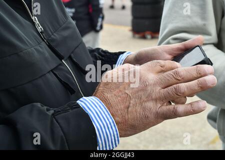 Uomo che cerca sul telefono touch screen circondato da una custodia in gomma nera Foto Stock