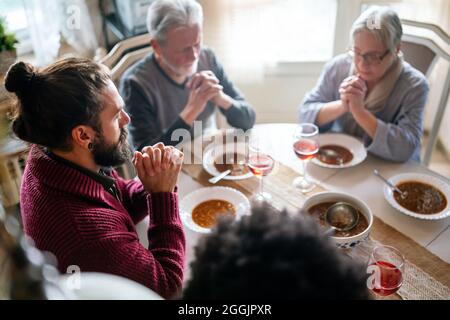 Famiglia e concetto religioso. Gruppo di persone multietniche con cibo che prega prima del pasto Foto Stock