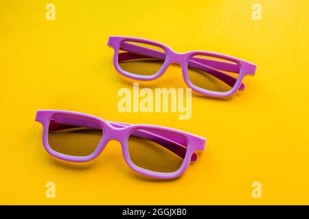 Un paio di occhiali 3d per guardare un film giacciono su uno sfondo giallo. Foto Stock