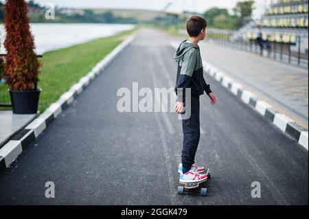 Il ragazzo adolescente in un abito sportivo corre a bordo di un longboard. Foto Stock