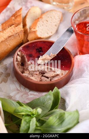 Delicato piatto di pollo con mirtilli di canna, addensato in gelatina. Servito con pezzi di baguette e drink di frutta Foto Stock