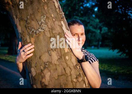 mano donna che abbraccia un albero nella foresta - la natura che ama, combattere il riscaldamento globale, salvare il pianeta terra Foto Stock