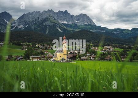 Giallo chiesa locale a Ellmau. Villaggio di andare. Montagne Wilden Kaiser sullo sfondo. Tirolo, Alpi, Austria Foto Stock