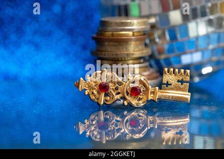 Chiave d'oro vintage, con una pila di monete e una palla da discoteca, sfocata sullo sfondo. Concetto creativo che rappresenta la chiave per il successo Foto Stock