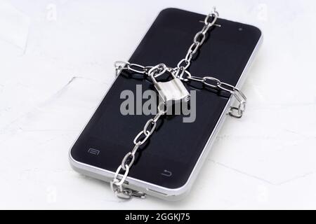 Primo piano di uno smartphone bloccato da un blocco a catena. Concetto di privacy dei dati. Concetto di sicurezza mobile e protezione dei dati personali. Foto Stock